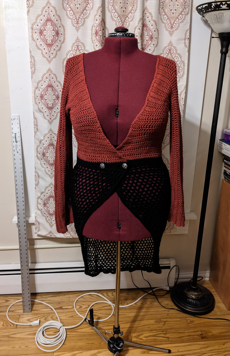 A deep-v cutaway sweater in rusty red and black cotton blend on a dress form