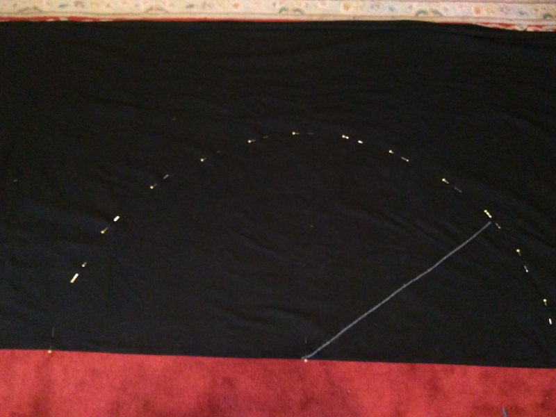 Folded fabric marked out with a pin and using a piece of yarn to measure the circle of the waist